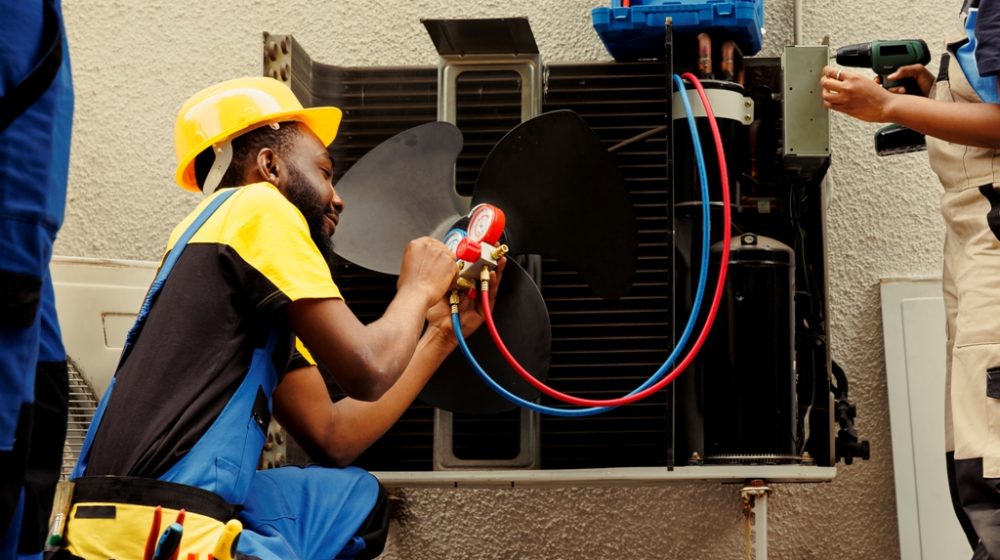 Worker refilling HVAC system refrigerant